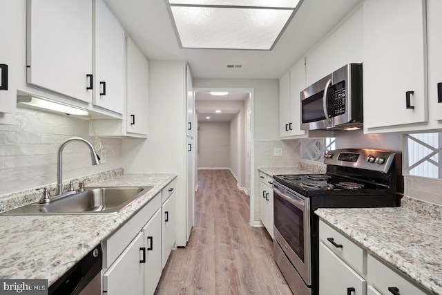 kitchen featuring visible vents, a sink, decorative backsplash, stainless steel appliances, and white cabinets