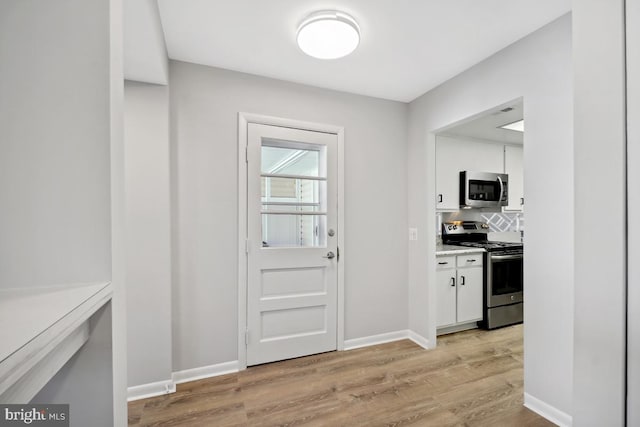 doorway to outside featuring baseboards and light wood-type flooring