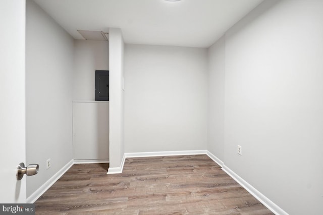 unfurnished room featuring electric panel, wood finished floors, and baseboards