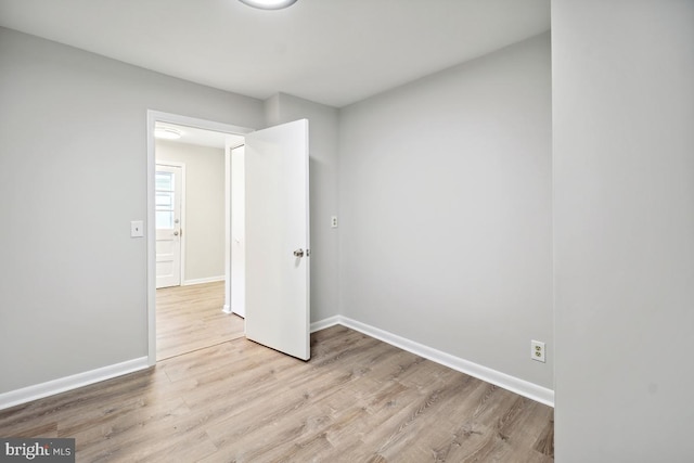 empty room featuring baseboards and light wood finished floors