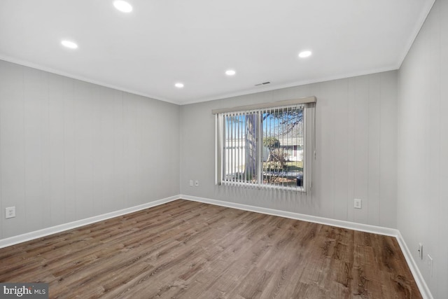 empty room with visible vents, baseboards, wood finished floors, and ornamental molding