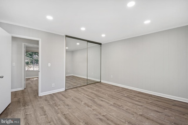 unfurnished bedroom with a closet, recessed lighting, baseboards, and wood finished floors