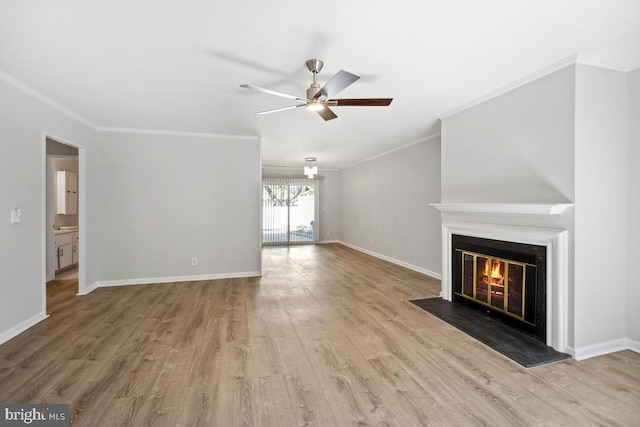 unfurnished living room featuring a glass covered fireplace, wood finished floors, baseboards, and ceiling fan