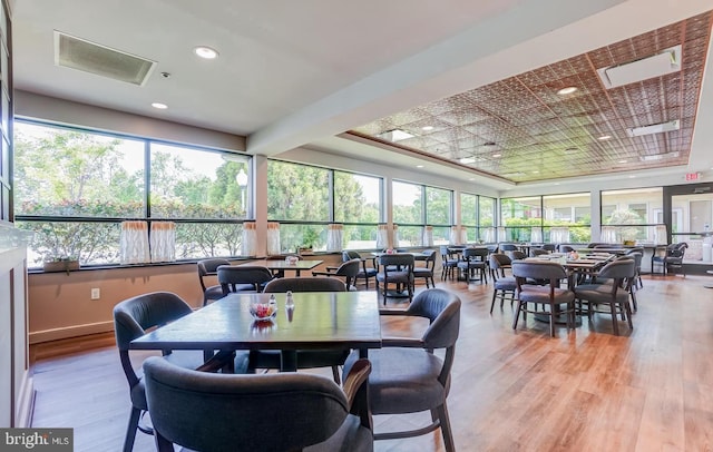 dining space with a tray ceiling, recessed lighting, and light wood finished floors