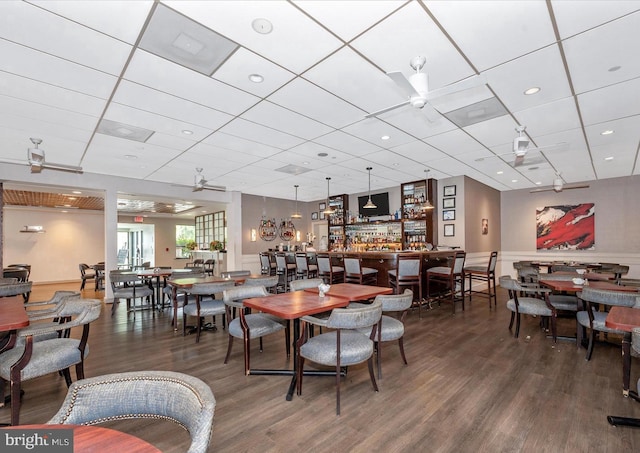 dining area featuring a drop ceiling, a ceiling fan, and wood finished floors