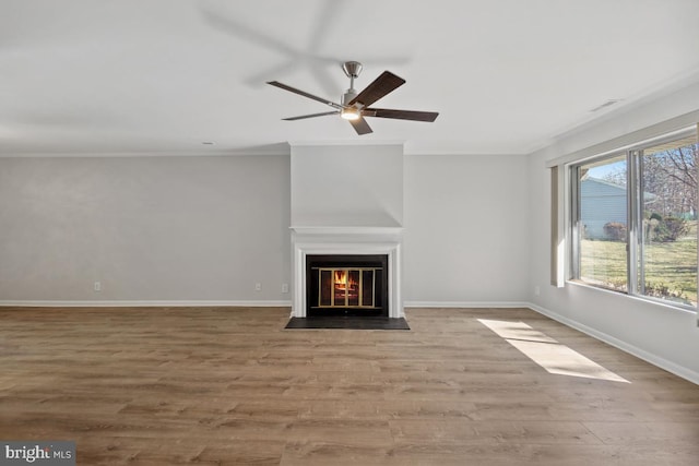 unfurnished living room with baseboards, a fireplace with flush hearth, wood finished floors, and crown molding