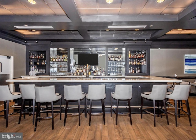 bar with hardwood / wood-style flooring, a community bar, coffered ceiling, and beam ceiling