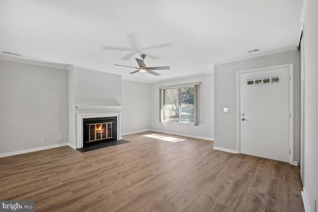 unfurnished living room with visible vents, a fireplace with flush hearth, baseboards, and wood finished floors