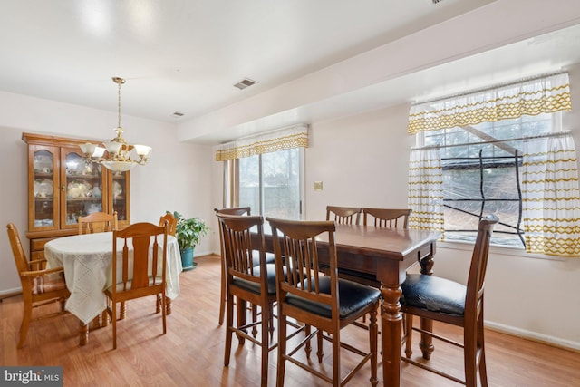 dining room with light wood-type flooring, an inviting chandelier, visible vents, and baseboards