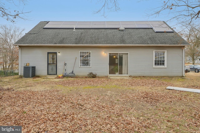 back of property featuring a shingled roof, roof mounted solar panels, and central AC