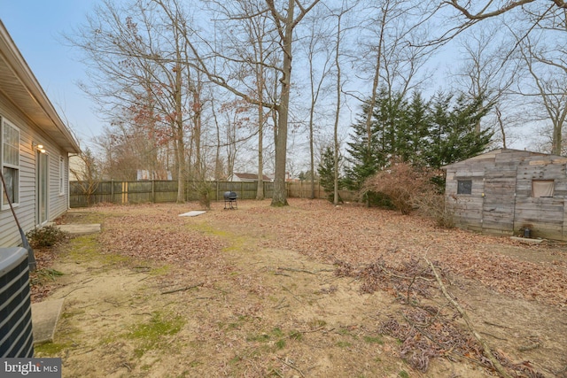 view of yard with an outbuilding, a fenced backyard, cooling unit, and a storage unit