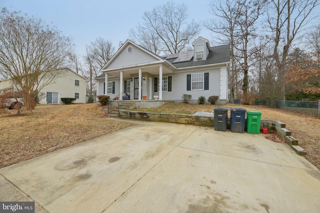 greek revival house with solar panels, a porch, and fence