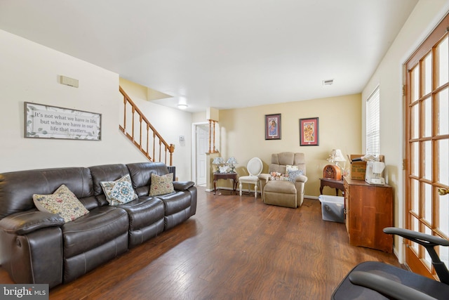 living room featuring stairs, visible vents, and dark wood finished floors