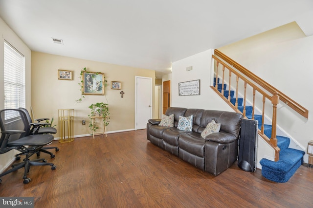 living room with dark wood-type flooring, visible vents, baseboards, and stairs