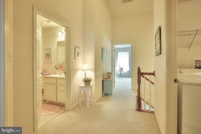 hall with light carpet, washer / clothes dryer, visible vents, and an upstairs landing