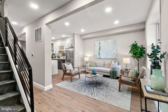 living area featuring light wood-style flooring, stairway, visible vents, and recessed lighting