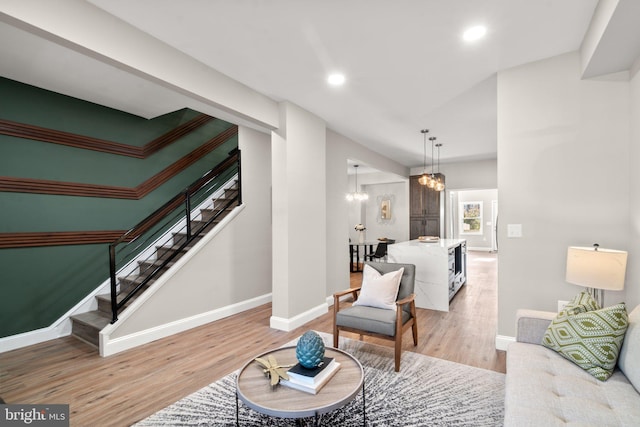 living area with baseboards, stairway, an inviting chandelier, light wood-type flooring, and recessed lighting