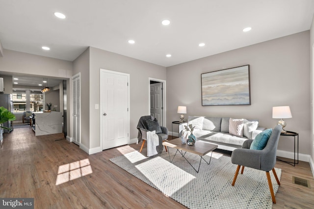 living area featuring baseboards, wood finished floors, visible vents, and recessed lighting