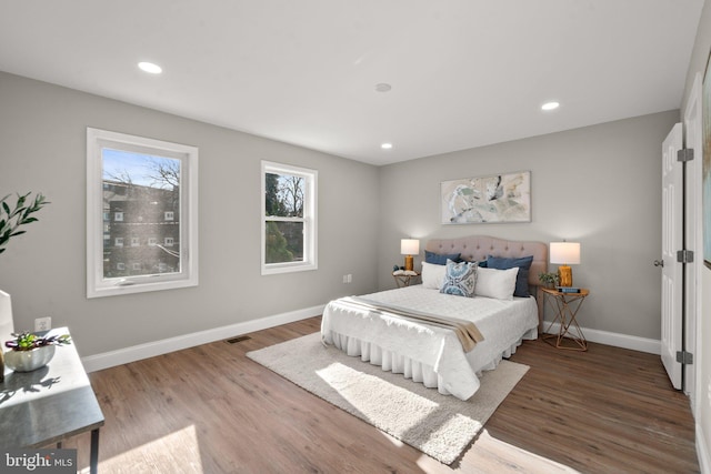 bedroom featuring visible vents, baseboards, wood finished floors, and recessed lighting