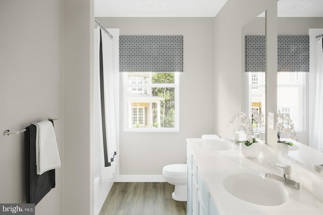 full bathroom with double vanity, a sink, toilet, and wood finished floors