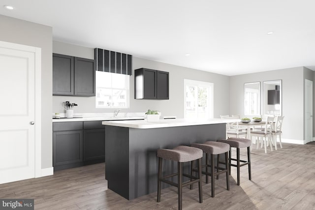 kitchen with a kitchen bar, light wood-style flooring, a kitchen island, and light countertops