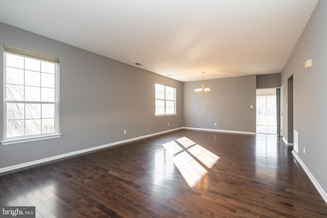 spare room with an inviting chandelier, visible vents, baseboards, and dark wood finished floors