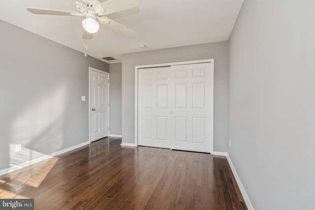 unfurnished bedroom featuring baseboards, a closet, visible vents, and dark wood-type flooring