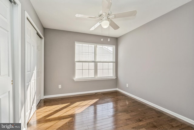 unfurnished bedroom with dark wood-style floors, a ceiling fan, baseboards, and a closet