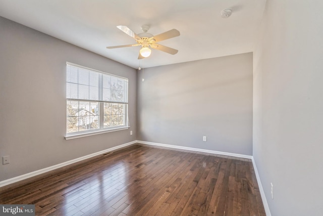 spare room with ceiling fan, visible vents, baseboards, and dark wood-type flooring