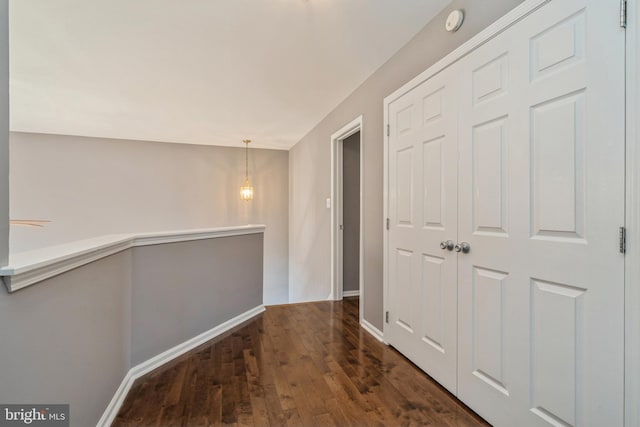 corridor featuring baseboards and dark wood finished floors