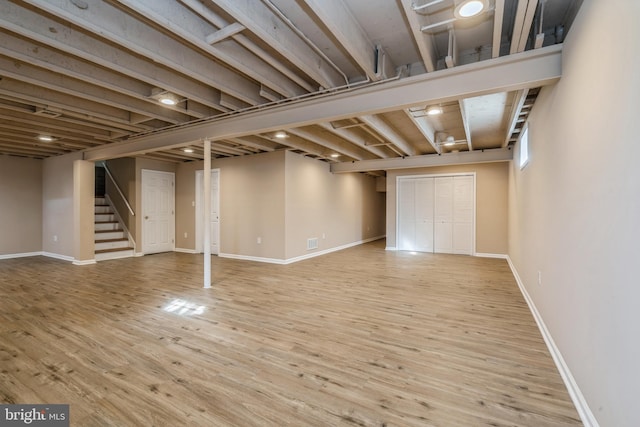 finished below grade area featuring stairway, light wood-type flooring, and baseboards