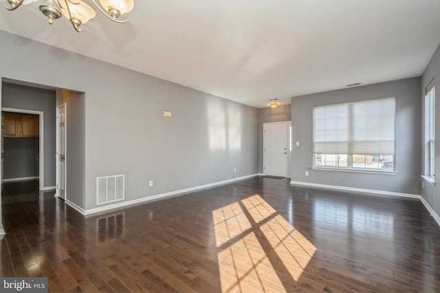 interior space featuring a notable chandelier, dark wood finished floors, visible vents, and baseboards