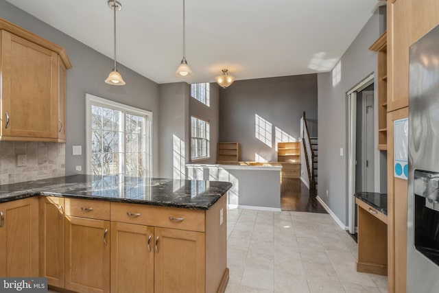 kitchen with baseboards, stainless steel refrigerator with ice dispenser, backsplash, dark stone counters, and pendant lighting