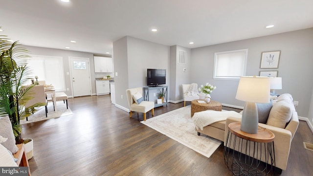 living area featuring baseboards, dark wood finished floors, and recessed lighting