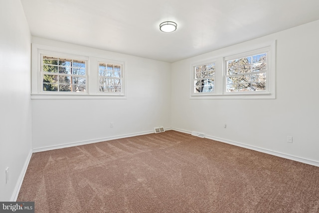 carpeted empty room with visible vents and baseboards