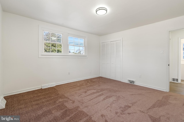 spare room with baseboards, visible vents, and dark carpet