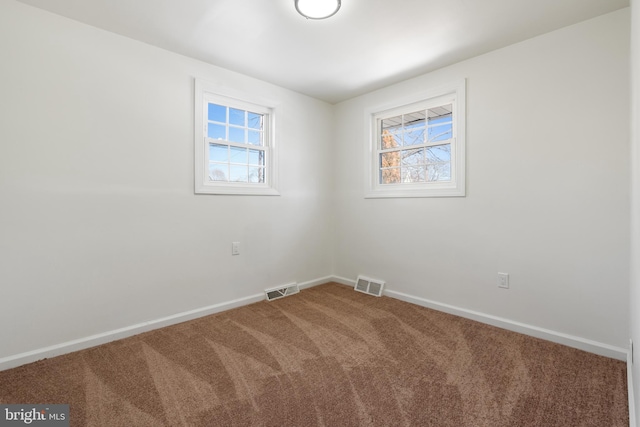 spare room featuring carpet floors, visible vents, and baseboards