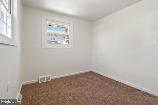 empty room with carpet floors, visible vents, and baseboards