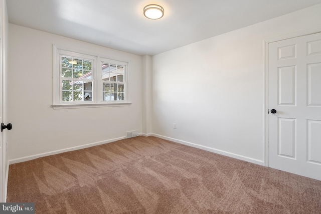 carpeted spare room featuring baseboards and visible vents