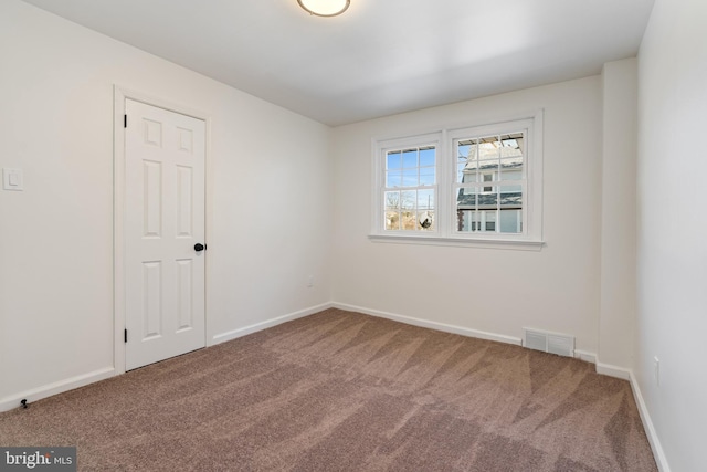 empty room with carpet floors, baseboards, and visible vents