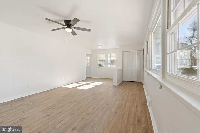 unfurnished living room with light wood-type flooring, ceiling fan, and baseboards