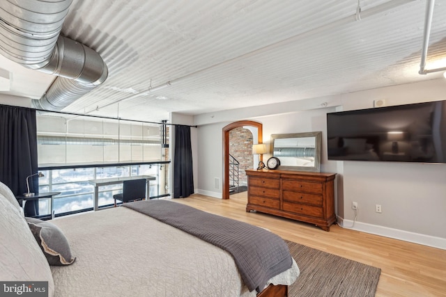 bedroom featuring arched walkways, baseboards, and wood finished floors