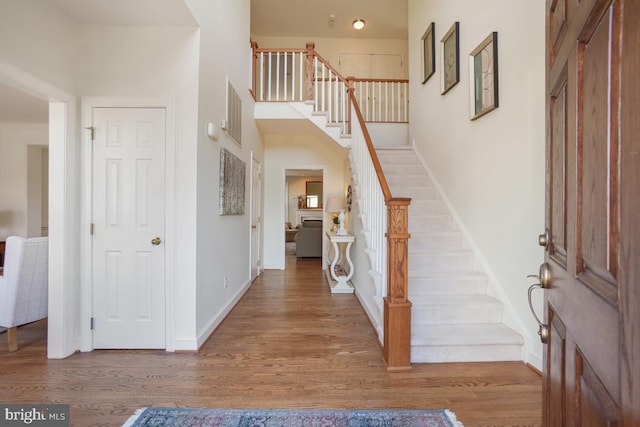 entryway with stairway, wood finished floors, and baseboards