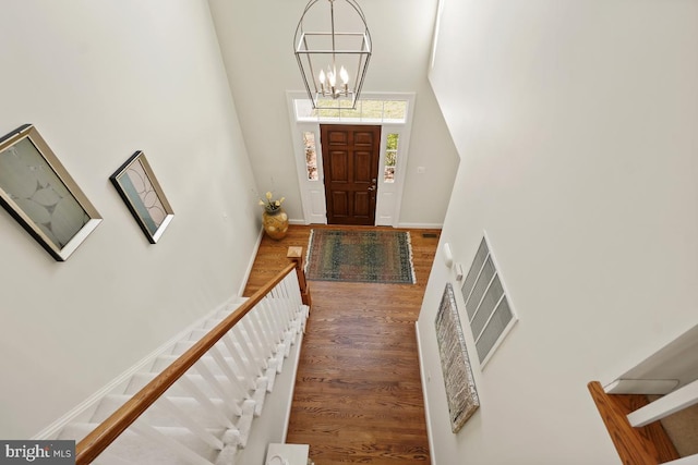 foyer with visible vents, baseboards, stairway, wood finished floors, and an inviting chandelier