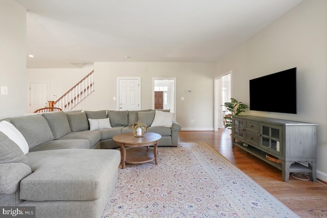 living area with stairs, baseboards, and wood finished floors