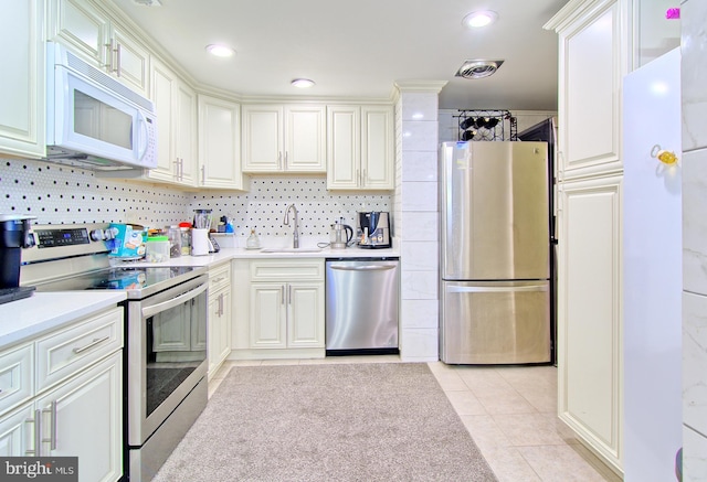 kitchen with a sink, stainless steel appliances, light tile patterned flooring, and light countertops