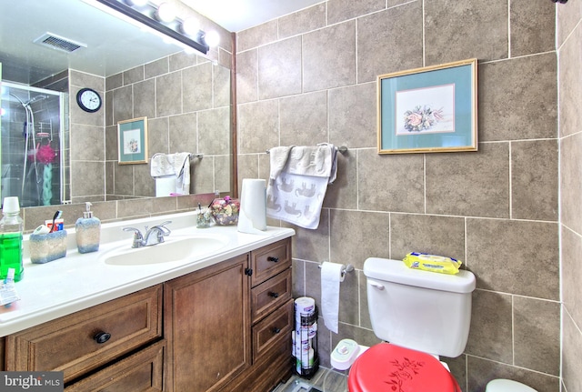 full bath featuring toilet, visible vents, tile walls, and vanity