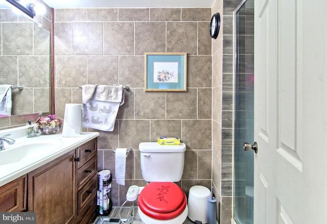 bathroom with tile walls, vanity, toilet, and an enclosed shower