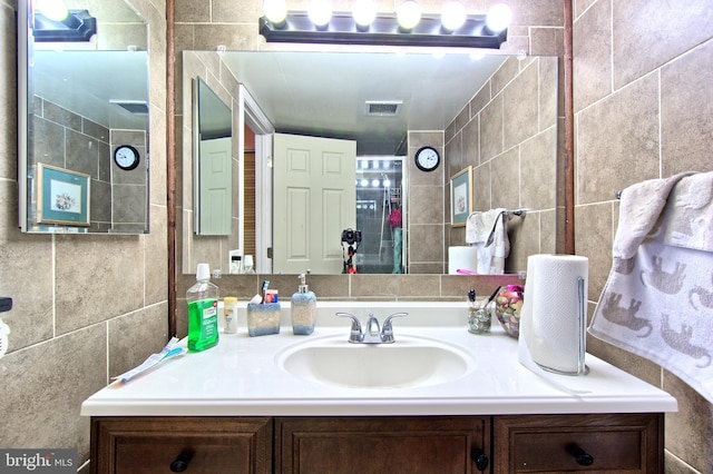 bathroom with vanity, visible vents, and tile walls