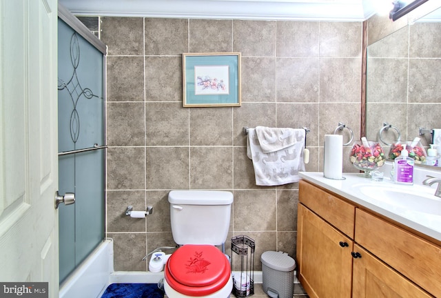 bathroom with toilet, bath / shower combo with glass door, tile walls, and vanity